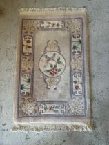 A grey rug with central motif and border (106cm X 60cm)