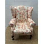 A white ground floral upholstered wing back arm chair on cabriole legs (H110cm W78cm D70cm)