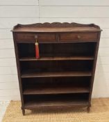 A four shelf oak bookcase with two drawers over and carved floral gallery (H117cm W93cm D23cm)