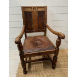 An oak carved leather seated arm chair on turned supports and legs