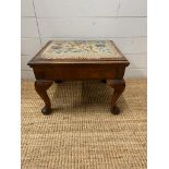 A mahogany foot stool on cabriole legs with floral upholstery opening to storage (H33cm W45cm