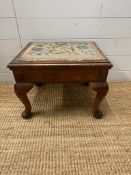 A mahogany foot stool on cabriole legs with floral upholstery opening to storage (H33cm W45cm