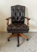 A faux brown leather button back desk chair on castors (H94cm W58cm D50cm)