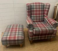 A check upholstered wing back arm chair and matching foot stool