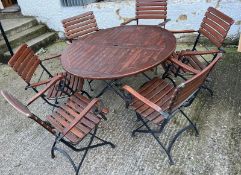 A Teak Garden circular table with wrought iron folding legs along with six matching chairs.