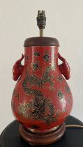 A red ground Oriental vase with ornate dragon design and dragon head handles. H 44cm