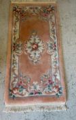 A pink ground rug with central floral motif (126cm x 58cm)