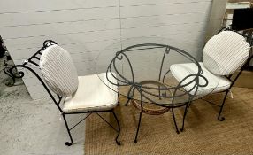 A wrought iron glass top garden table with two wrought iron chair with cream cushions (H75cm
