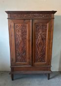 A hand carved vintage oak two door cupboard on raised feet with two inner shelves AF (H166cm D40cm