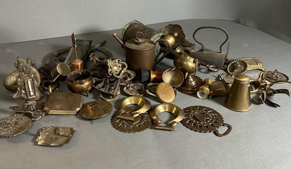 A large selection of brass and copper curios including door knockers, syringe, horse brasses etc.