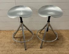 A pair of industrial style adjustable swivel stools, chrome legs and moulded steel saddle seats
