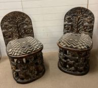 A pair of carved seats with tribal theme carving to back and base (H97cm W54cm D50cm SH54cm)