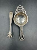 A silver tea strainer and a pair of hallmarked silver sugar nips.