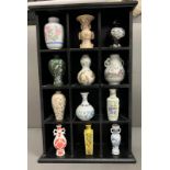 Twelve miniature porcelain vases various styles in a wooden wall hanging display