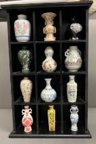 Twelve miniature porcelain vases various styles in a wooden wall hanging display