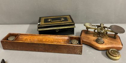 A metal cashbox and a wooden desk pen holder with inkwells to end and a brass letter scales with