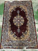 A silk rug with burgandy grounds, floral border and floral central medallion 148x100