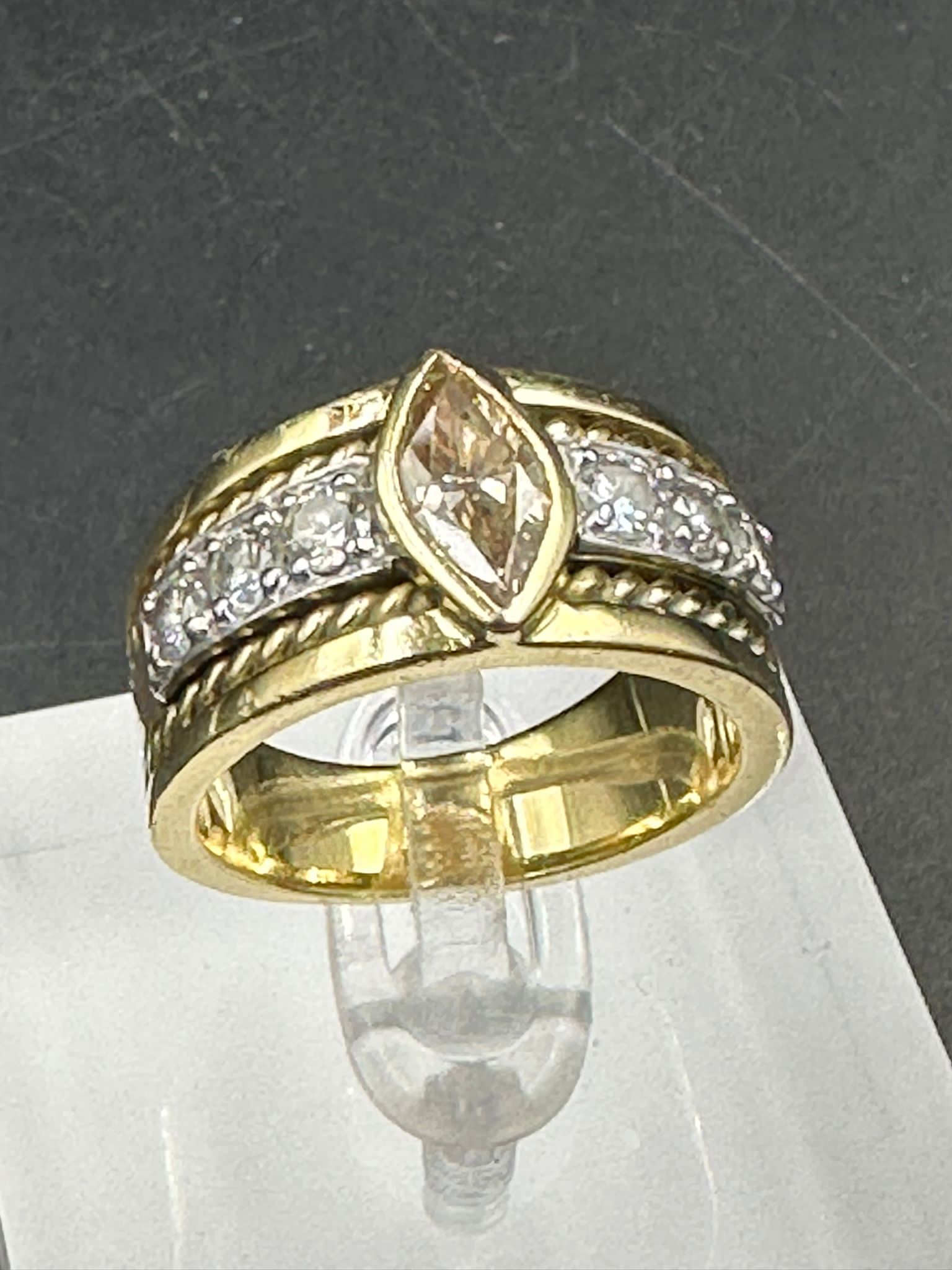 A yellow gold diamond ring with central stone and three separate diamonds to each side .