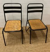 A pair of contemporary industrial style sacking chairs with wooden seat and metal hair pin style