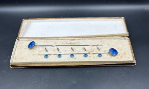 An case set of blue enamel hat pins and fasteners on white metal
