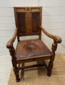 An oak carved leather seated arm chair on turned supports and legs