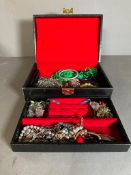 A Black jewellery box with a selection of costume jewellery including a silver enamel bracelet.