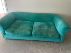 An upholstered teal velvet sofa