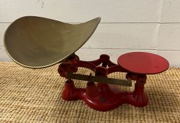 A set of red weighing scales with a brass bowl