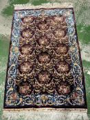 A silk rug with burgandy grounds floral blue ground border and central floral motif 148x100