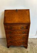 A bow fronted flame mahogany four drawer, ladies bureau opening to green leather writing surface,
