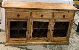 A pine sideboard with three drawers and cupboards under with metal grill fronts (H91cm W153cm