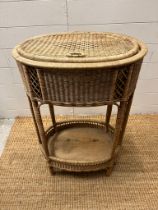 An oval wicker side table (H75cm W54cm D35cm)