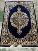 A silk rug with blue grounds and gold scrolling border and central scrolling medallion 148x100