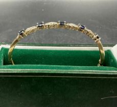 A 9ct gold bangle with diamond and precious stones (7.2g)