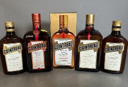 Five bottles of Cointreau, various sizes.