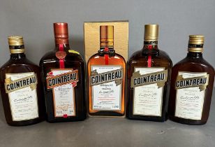Five bottles of Cointreau, various sizes.