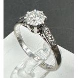 A single stone diamond ring with diamond set shoulders. Round Brilliant cut diamond 0.64ct, Colour