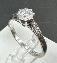 A single stone diamond ring with diamond set shoulders. Round Brilliant cut diamond 0.64ct, Colour