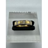 An 18ct white and yellow gold band inset with three small diamonds, approximate size \m and weight