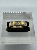 An 18ct white and yellow gold band inset with three small diamonds, approximate size \m and weight