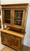 A pine dresser with glazed top on turned supports and cupboards (H204cm W123cm D57cm)