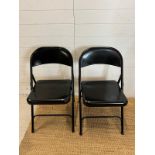 A pair of black metal folding chairs