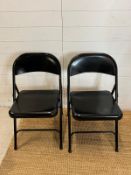 A pair of black metal folding chairs