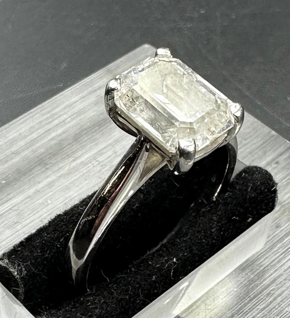 A 3.26ct emerald cut diamond which commercial White and PK3 quality, four claw platinum set on a