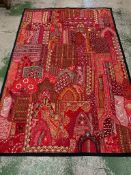 An Indian needlework panelled textile in reds and pinks silks and cottons with mirrored inlay and