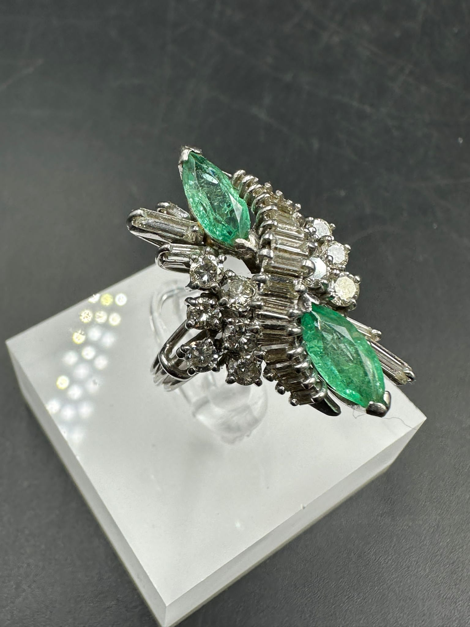 An emerald and diamond ring, designed a s a vertically set elongated cluster with two marquise cut