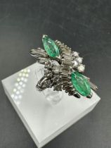 An emerald and diamond ring, designed a s a vertically set elongated cluster with two marquise cut