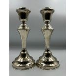A Pair of filled silver candlesticks by hallmarked for London 1922, makers marks JE