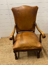 A leather and mahogany arm chair with scrolling arms and curved supports