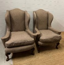 A pair of wing back chairs on carved feet